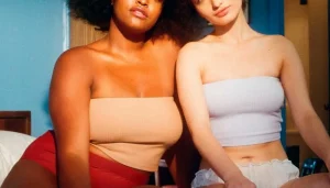 Deux femmes en lingerie sur un lit, l’une avec une forte poitrine et l’autre avec une poitrine menue, illustrant l’augmentation et la réduction mammaire à Marseille